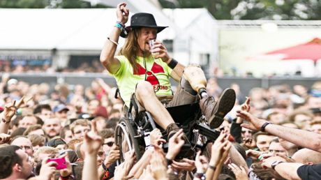 Ein Festivalbesucher im Rollstuhl wird über die Köpfe der Besucher*innen gehoben