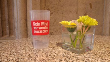 Mehrwegbecher und Blumen in Vase